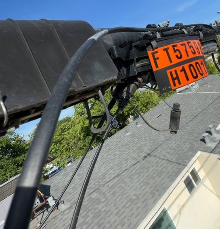 Aerial fibre distribution terminal with identification placard above a rooftop