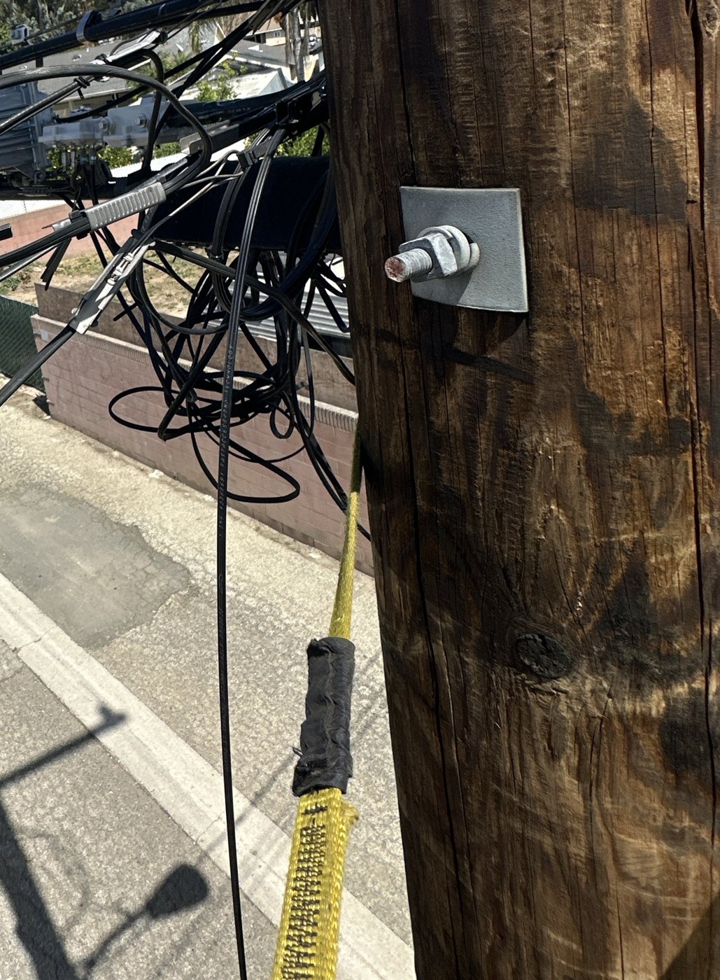 Aerial fibre plant on a congested utility pole, photographed by a technician at height