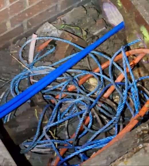 Tangle of blue and orange conduit cables inside an underground chamber